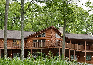 Cedar log home with large deck surrounded by trees