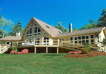 Yellow-ochre log home with large windows and deck