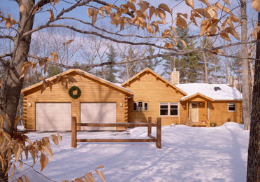 Log home in snow with wreath on garage