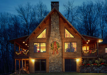 Cedar log home with wreath and lights at dusk
