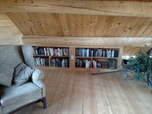Loft area with wooden bookshelves and a cozy armchair.