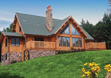 Log home with stone chimney and large windows