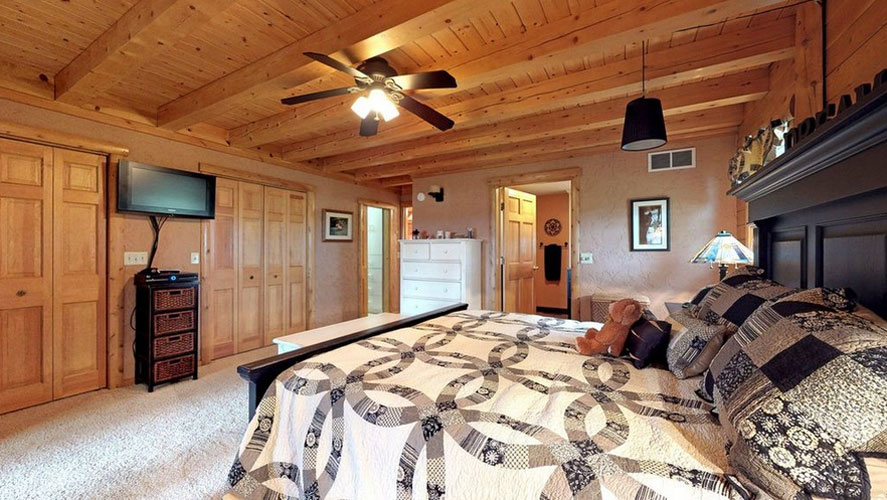 Cozy bedroom with wooden ceiling and quilted bedspread