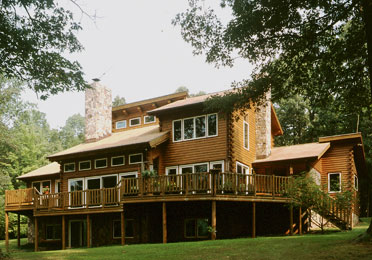 Log home with large windows and wooden deck