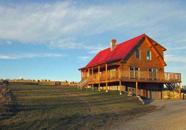 Log home with red roof and wraparound porch