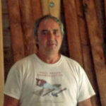 Paul Baker standing in front of wooden logs