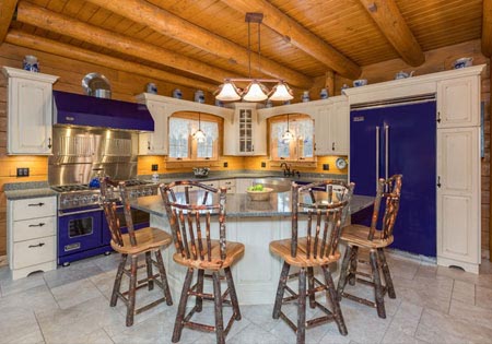 Log cabin kitchen with wooden beams, island, and rustic chairs.