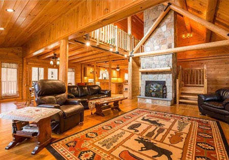 Spacious log cabin living room with stone fireplace and leather sofas.