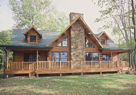 Log home with large windows and stone chimney