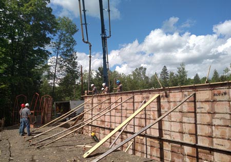 Workers constructing a concrete foundation with trees in background