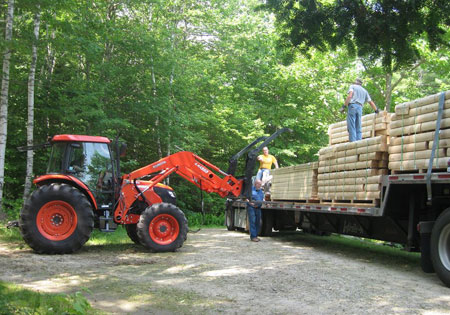 Forklift unloading logs from a delivery truck in forest