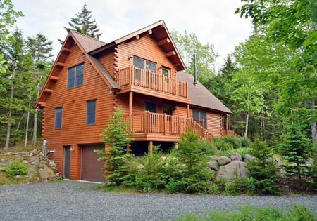 Two-story cedar log home surrounded by trees