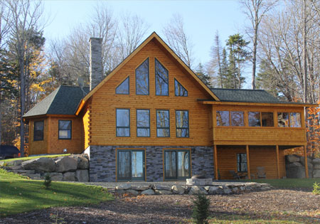 Cedar log home with large windows surrounded by trees
