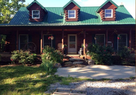 Cedar log home with green metal roof and three dormers