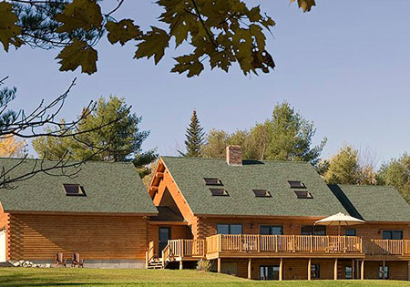 Cedar log home with green roof and trees