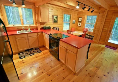 Log cabin kitchen with red countertops and wooden cabinets