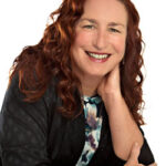 Smiling woman with curly red hair in a black jacket