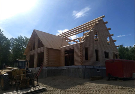 Partially built log home with exposed beams and clear sky