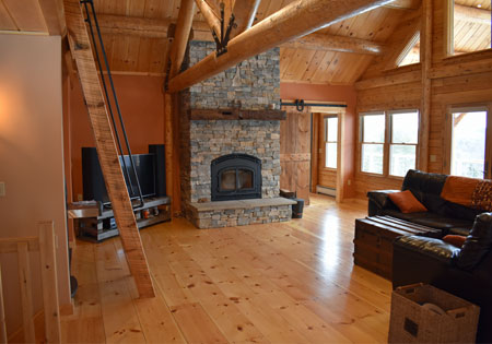 Spacious log home living room with stone fireplace