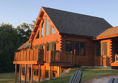 Cedar log home with large windows and deck