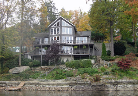 Large cedar log home by a lake surrounded by autumn trees