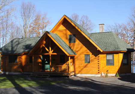 Cedar log home with green roof and porch