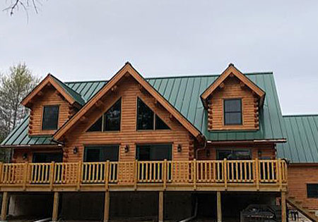 Front view of a cedar log home with green roof