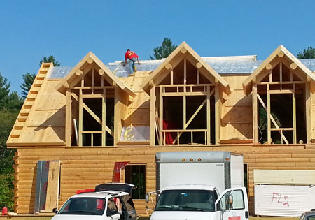 Worker on roof of log home under construction