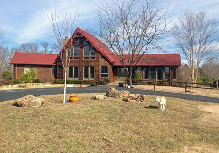 Log home with red roof and bare trees in yard