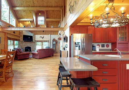 Open kitchen with red cabinets and living room with leather sofas