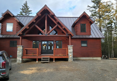 Log home with large windows and wooden porch