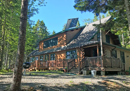 Log home with solar panels surrounded by trees