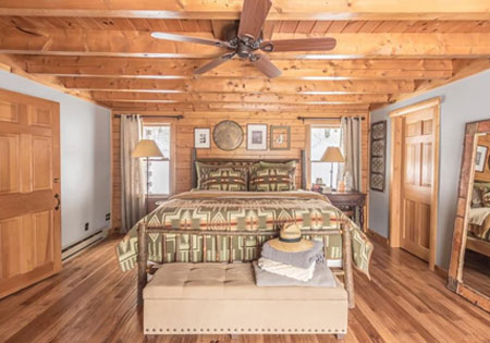 Log cabin bedroom with wooden ceiling and cozy decor