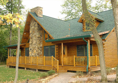 Log home with stone chimney surrounded by trees