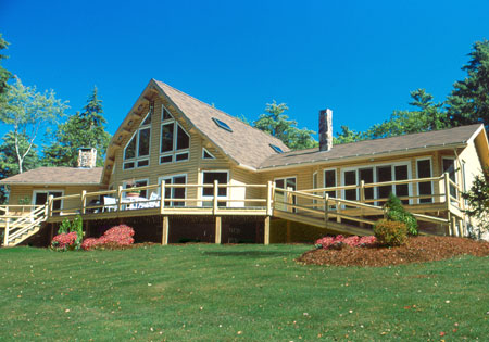 Large log home with triangular windows and wooden deck