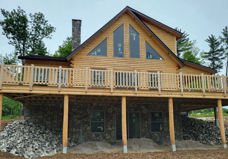 Two-story log home with stone base and wooden deck