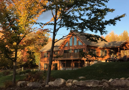 Log home surrounded by autumn trees and rocks