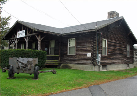 Rustic log cabin with a small cannon on lawn