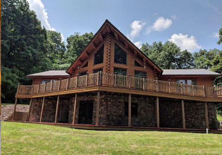 Log home with wooden deck and stone foundation