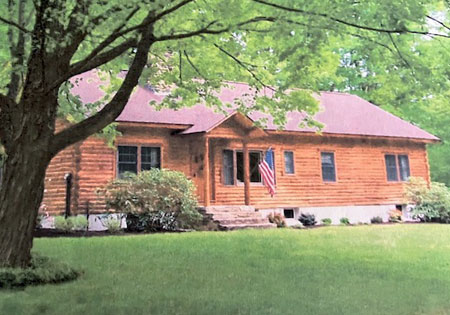 Cedar log home with front porch and American flag.