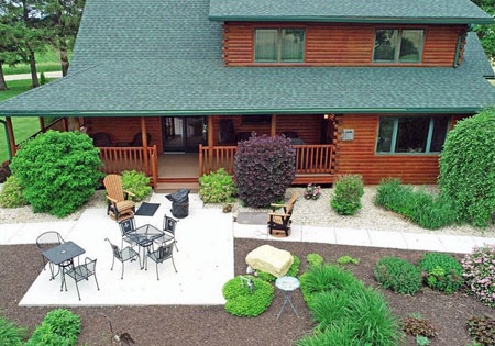 Log home with porch and garden view