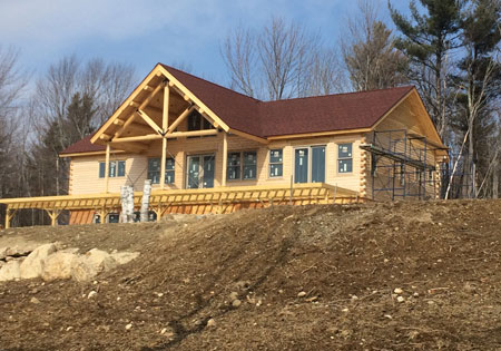 Log home under construction with wooden beams and red roof.