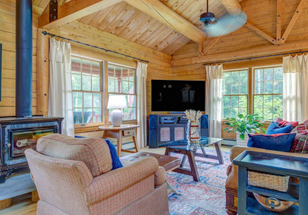 Living room with wooden walls, large windows, and cozy furniture