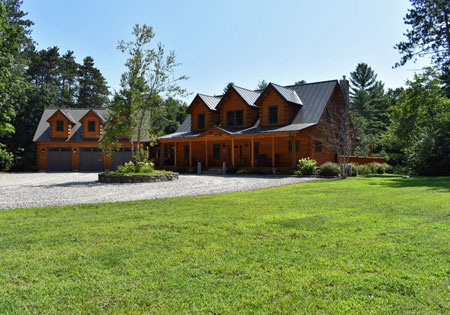 Log home with gabled roof and green lawn