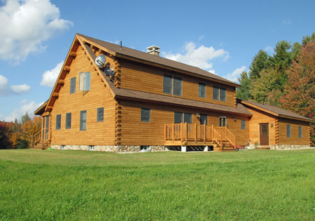 Large cedar log home with green lawn and trees
