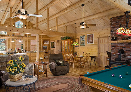 Spacious log home interior with wooden beams, furniture, and pool table.