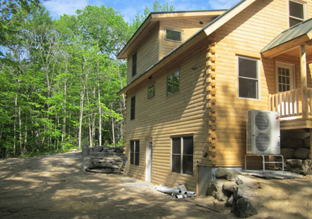 Two-story log home with trees and sunlight
