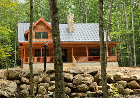 Log cabin with stone chimney surrounded by trees