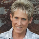 Headshot of Marydee Mock with short hair and plaid shirt