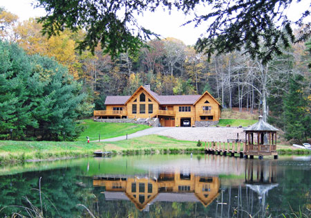 Log cabin with large windows by a lake in autumn